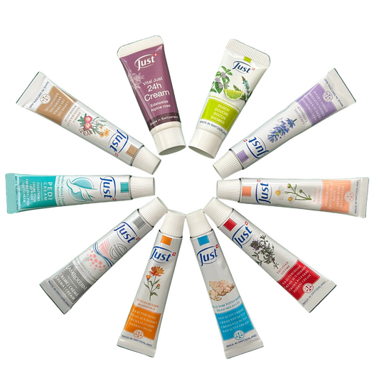 Eight tubes of Just Skin cream arranged in a circular pattern on a solid white background, showing different product colors and labels.